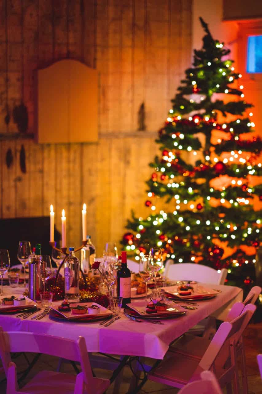 gedekte tafel voor zakelijk kerstdiner op boerderij met kerstboom in achtergrond